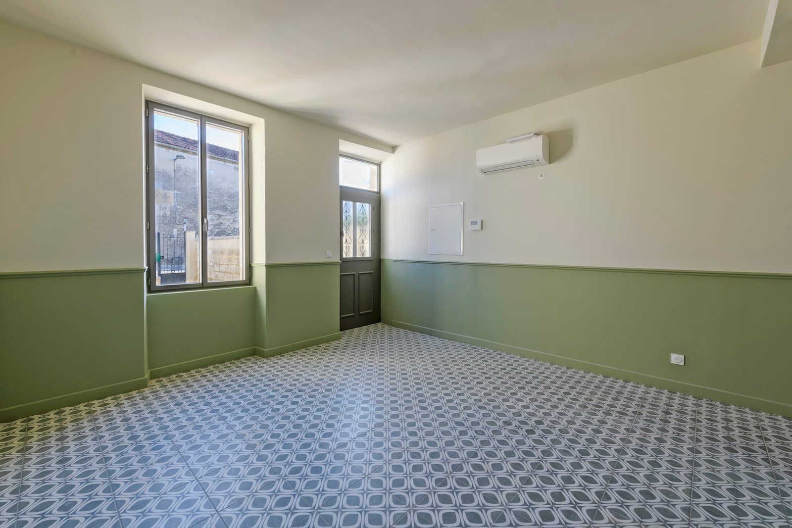 État actuel de la pièce avec murs verts et carrelage géométrique bleu